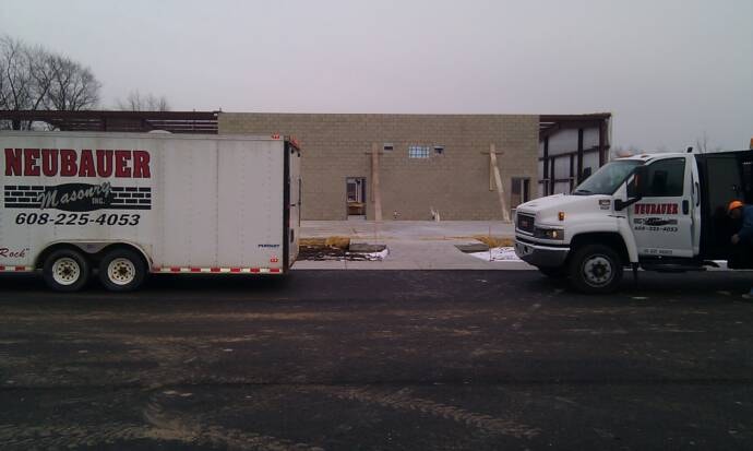 Neubauer Masonry enclosed tool trailer and GMC service truck at job site
