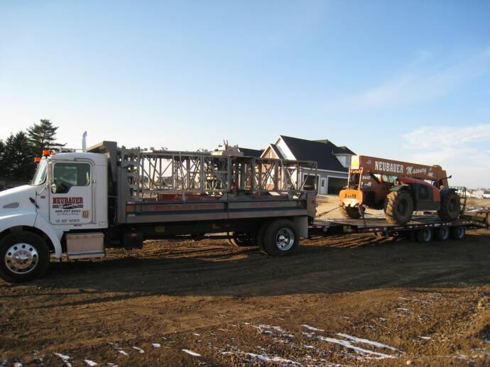 Neubauer Masonry truck towing scaffolding and telehandler on trailer